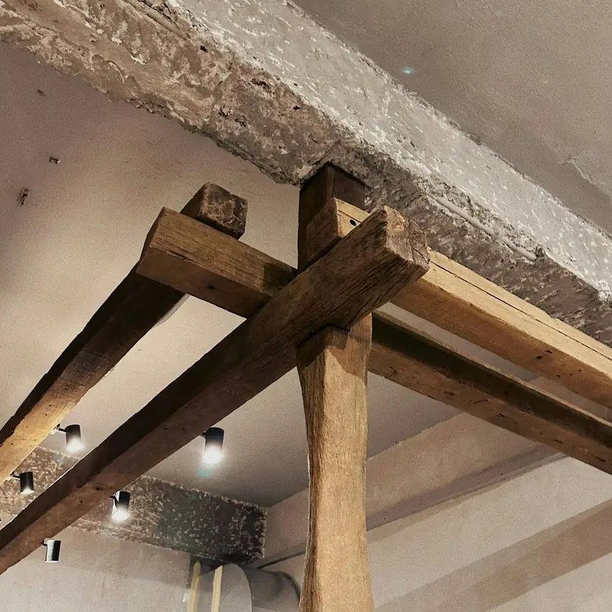 Old oak beams and a post under the pale ceiling of an attic
