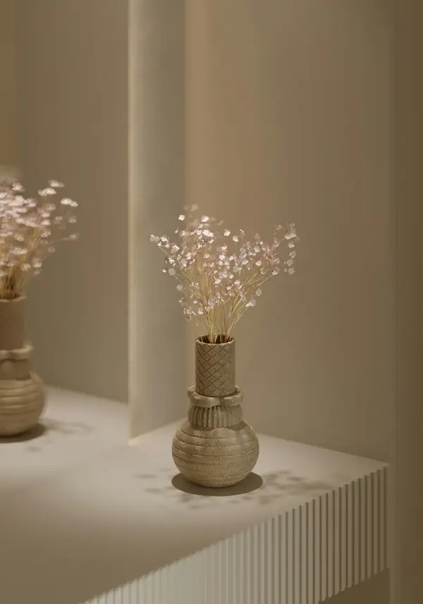 Clay vases with dried flowers on a windowsill by a smooth wall